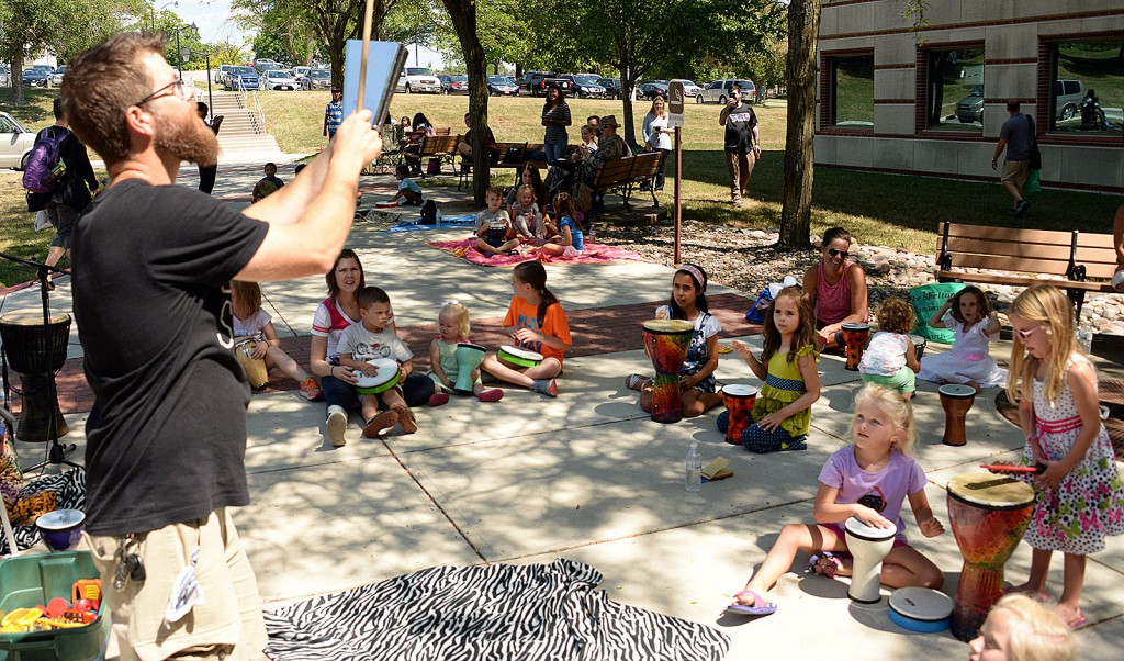 Joshua Conner, with the interactive children's music program Drum Safari, leads a call-and-response game, during which children repeat the rhythm he plays on a cowbell, at the Combined Arms Research Library's end-of-summer reading program July 27 outside the library. (photos by Prudence Siebert/Fort Leavenworth Lamp)