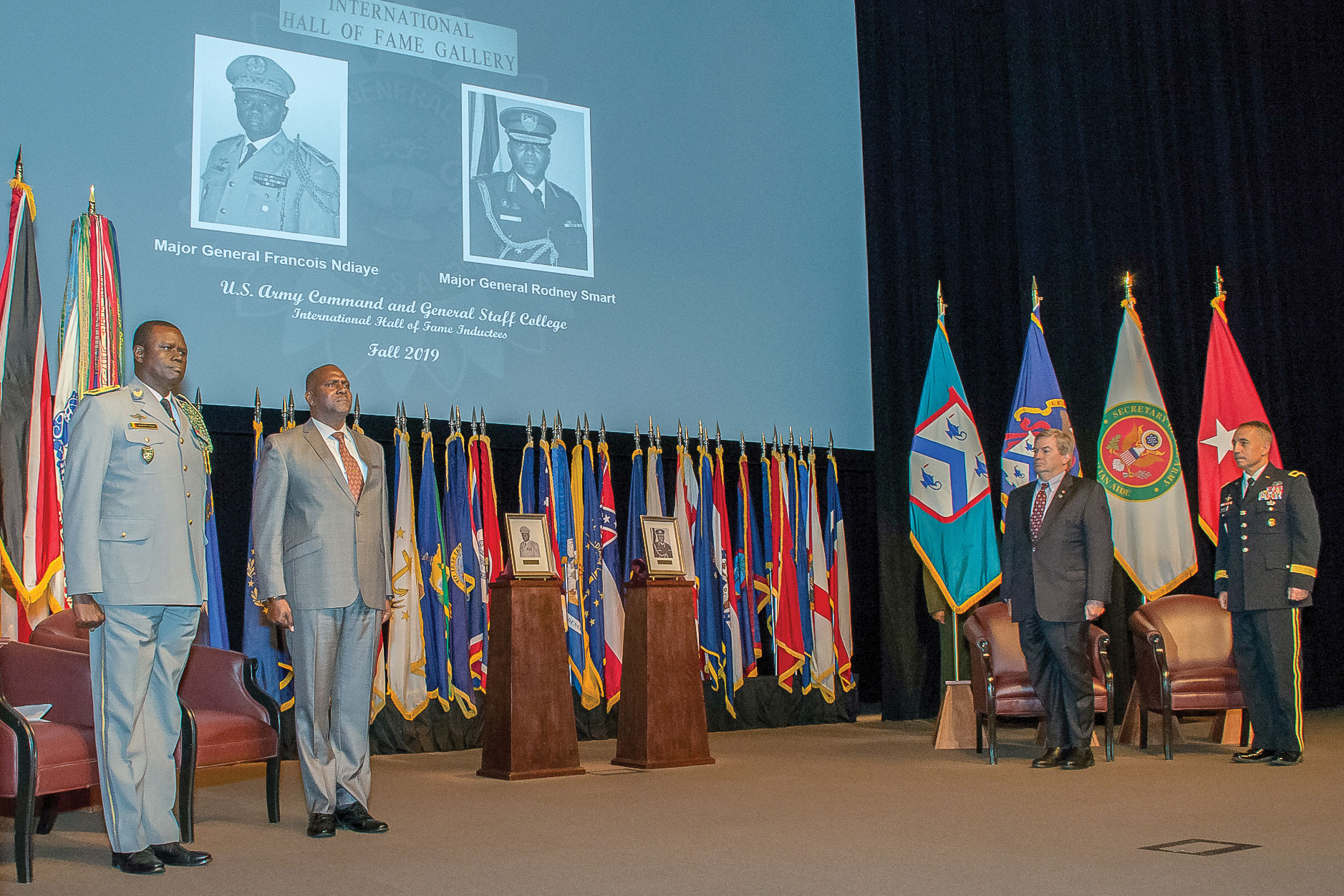 Photo of IHOF inductees Maj. Gen. Francois Ndiaye, chief of staff of the Senegalese Army, CGSC class of 1994; and retired Maj. Gen. Rodney Smart, former chief of Defence Staff of the Trinidad and Tobago Defence Force, CGSC class of 2009-01, along with CGSC Foundation Chairman Mike Hockley and CGSC Deputy Commandant Brig. Gen. Stephen Maranian stand at attention as the national anthems of each country are played at the end of the ceremony Oct. 3, 2019, at the Lewis and Clark Center.