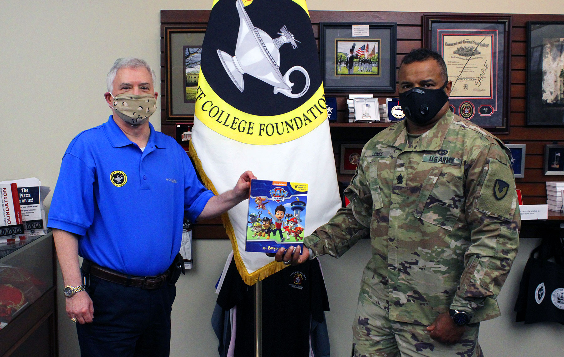 Fort Leavenworth Garrison Command Sgt. Maj. Antwone Jones accepts a book donation from Foundation CEO Rod Cox to support a FMWR event on July 25, 2020.