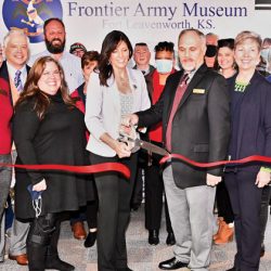 CGSC Foundation Director of Operations Lora Morgan (with scissors, left) and Frontier Army Museum Curator Russell Ronspies (right), flanked by other members of the Foundation, museum and the Leavenworth/Lansing Area Chamber of Commerce cut the ribbon signifying the CGSC Foundation's opening of operations of the museum's gift shop on Dec. 8, 2021.