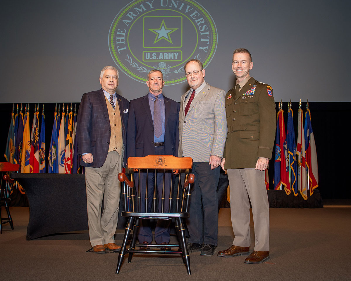 Dr. Jim Greer from the School of Advanced Military Studies receives a chair from the CGSC Foundation in recognition of his selection as the CGSC 2022 Civilian Educator of the Year during the faculty awards ceremony in the Lewis and Clark Center on April 4, 2022. From left, CGSC Foundation President/CEO Rod Cox, Greer, CGSC Dean of Academics Dr. Jack Kemp, and CGSC Deputy Commandant Maj. Gen. Donn H. Hill.