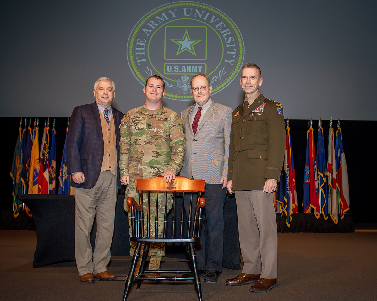 Lt. Col. Tim Tyner from the Department of Joint, Interagency and Multinational Operations in the Command and General Staff School receives a chair from the CGSC Foundation in recognition of his selection as the CGSC 2022 Military Educator of the Year during the faculty awards ceremony in the Lewis and Clark Center on April 4, 2022. From left, CGSC Foundation President/CEO Rod Cox, Tyner, CGSC Dean of Academics Dr. Jack Kemp, and CGSC Deputy Commandant Maj. Gen. Donn H. Hill.
