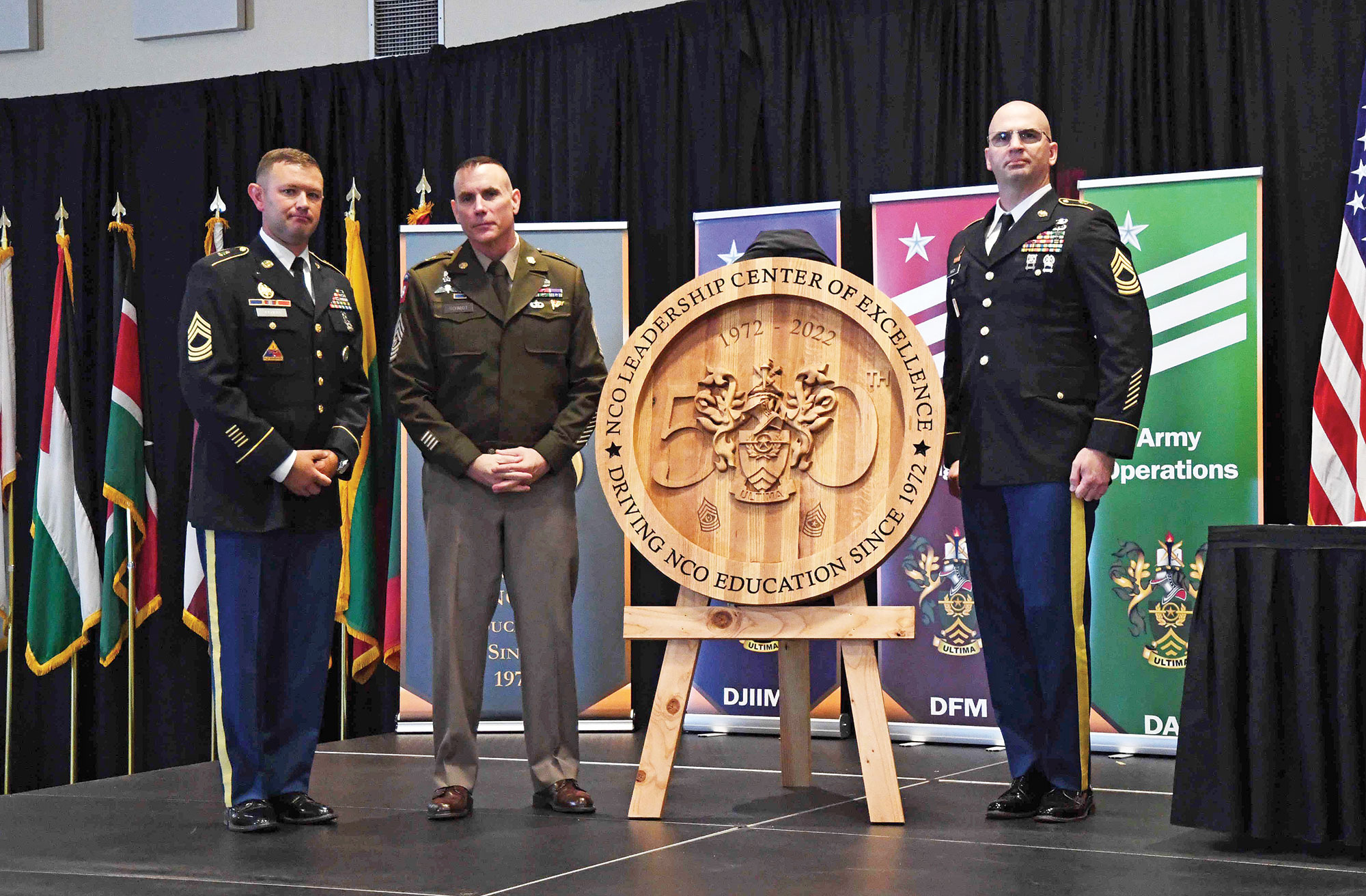 Master Sgt. Joshua Nardi (right) presents Command Sgt. Maj. Jason Schmidt, NCOLCoE and SGM-A commandant, with a 50th Anniversary Legacy Gift, a woodwork created by Nardi. Also pictured is Master Sgt. David Fisher of the 50th Anniversary Legacy Gift Committee.