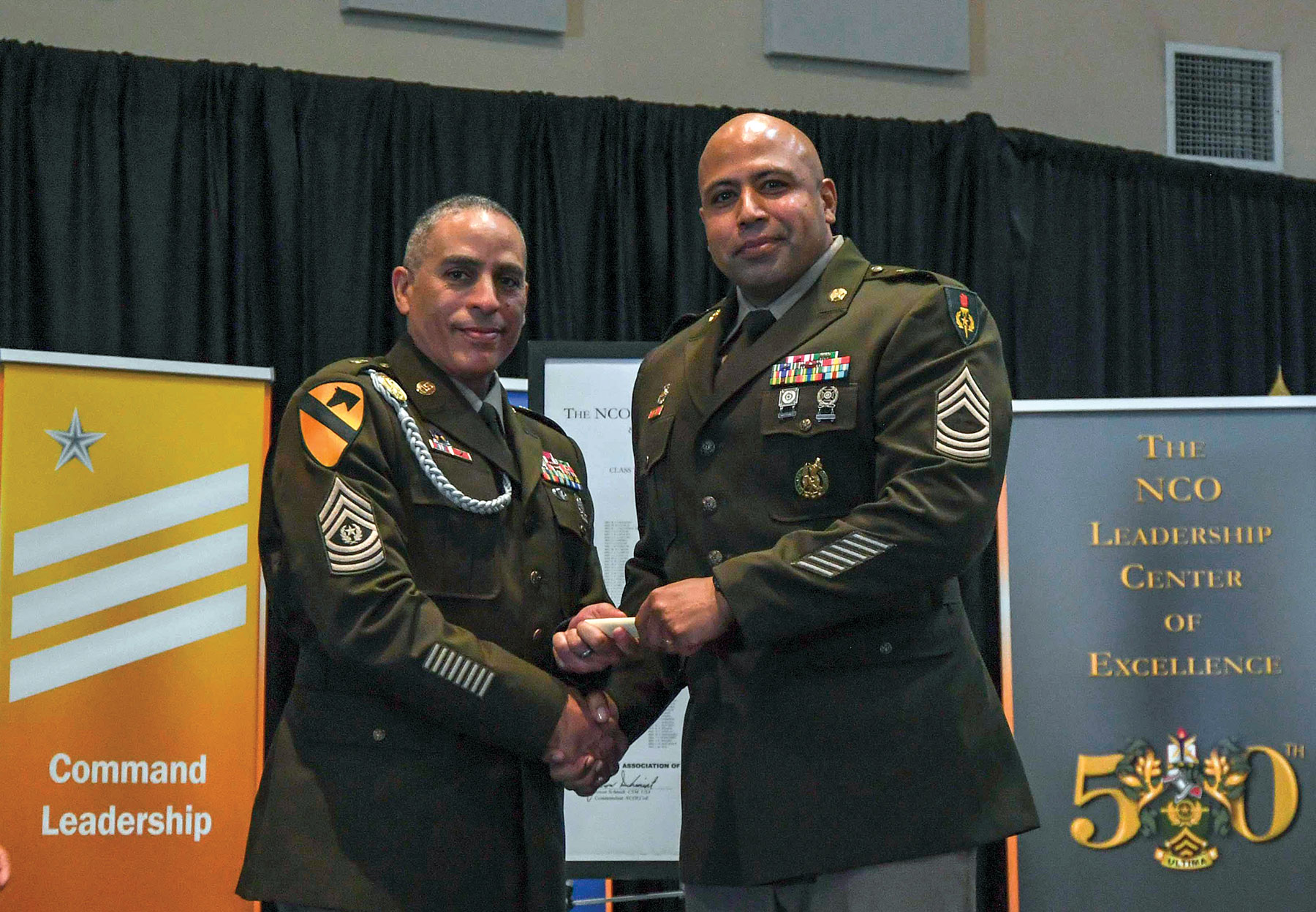 Master Sgt. Alberto Pena accepts his diploma from Command Sgt. Maj. Michael Arceneaux, Sergeants Major Academy director. (Photo by Andrew Smith, NCOLCoE Command Communications)