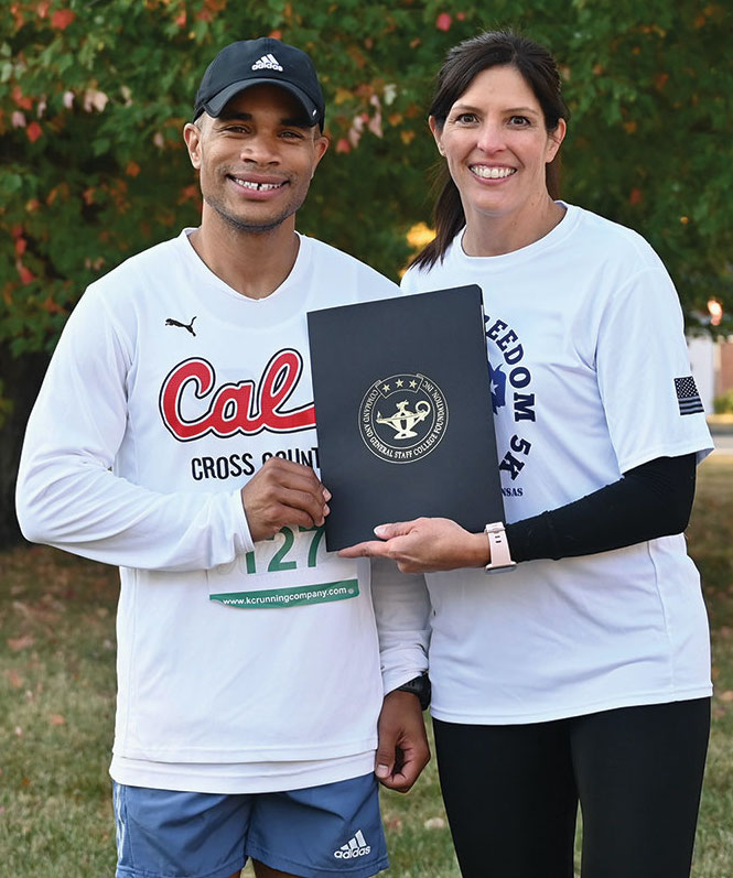 CGSC Foundation Director of Operations Lora Morgan, right, presents a certificate to Bradley Rager for his first place overall and top male division finish in the Frontier Freedom 5K Run/Walk on Fort Leavenworth on Oct. 9, 2022. The race was hosted by the CGSC Foundation and the Greater Kansas City Friends of the Fisher House. 