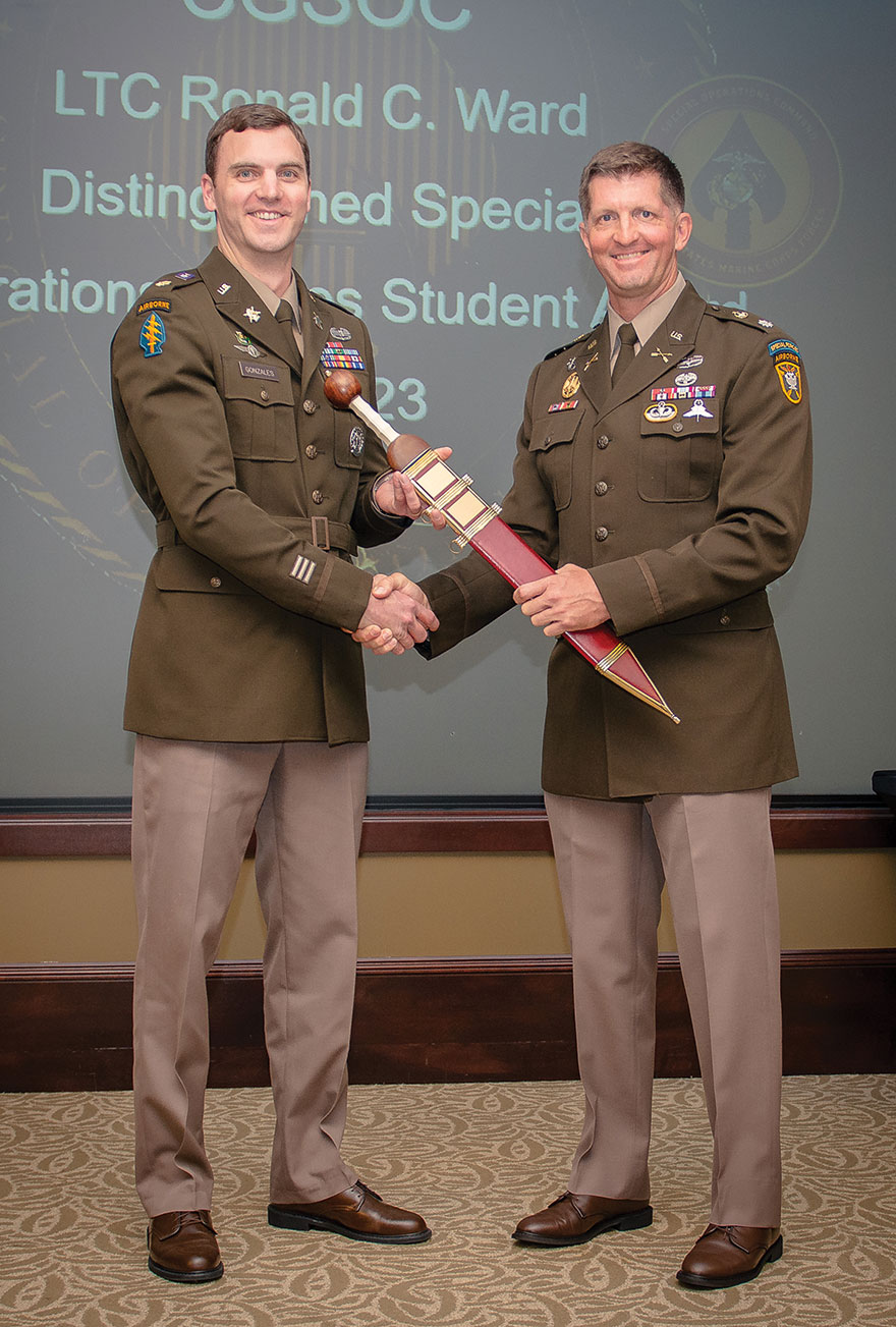 Maj. Kent J. Gonzales, left, receives the LTC Ronald C. Ward Distinguished Special Operations Forces Student Award, a Roman Gladius sword, signifying his selection as the top Special Operations Forces student for the Command and General Staff Officer Course Class of 2023 in a ceremony June 7 in the Arnold Conference Room of the Lewis and Clark Center. Presenting the award is Lt. Col. Steve Bolton, the director for Special Operations Leader Development and Education at Army University.