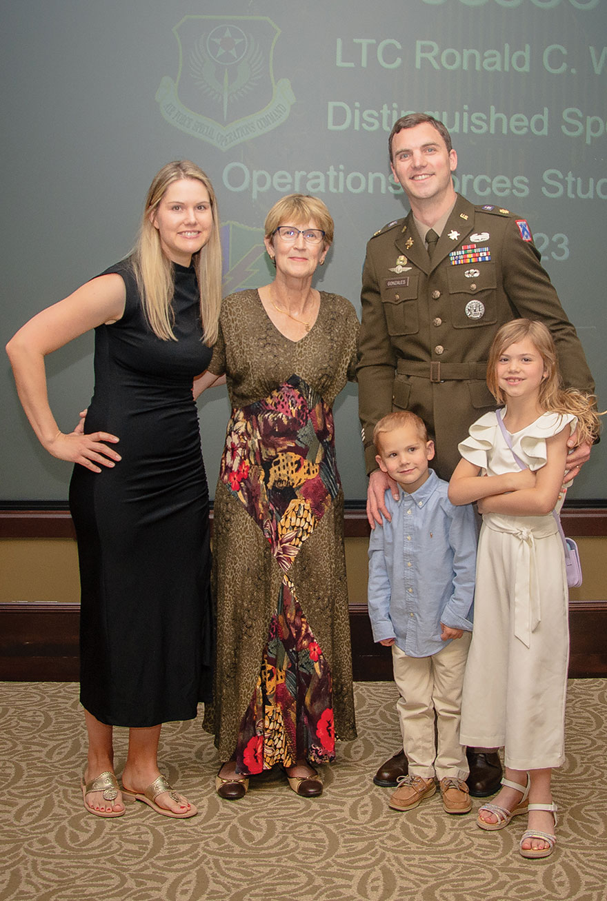 Maj. Kent J. Gonzales, right, the 2023 recipient of the LTC Ronald C. Ward Distinguished Special Operations Forces Student Award, his wife Haley, left, and two of their children, take a photo with Ms. Beth Ward, wife of the award’s namesake, during the ceremony June 7, 2023, in the Arnold Conference Room of the Lewis and Clark Center.