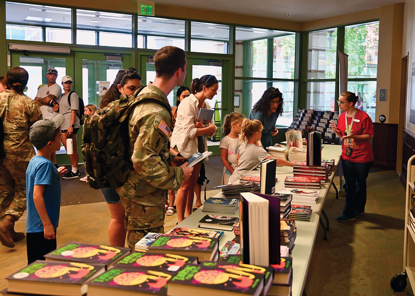 Library staff member Kristyn Crossley, right, assists kids with selecting their free book at the entrance to the Ike Skelton Combined Arms Research Library open house on Aug. 11, 2023.