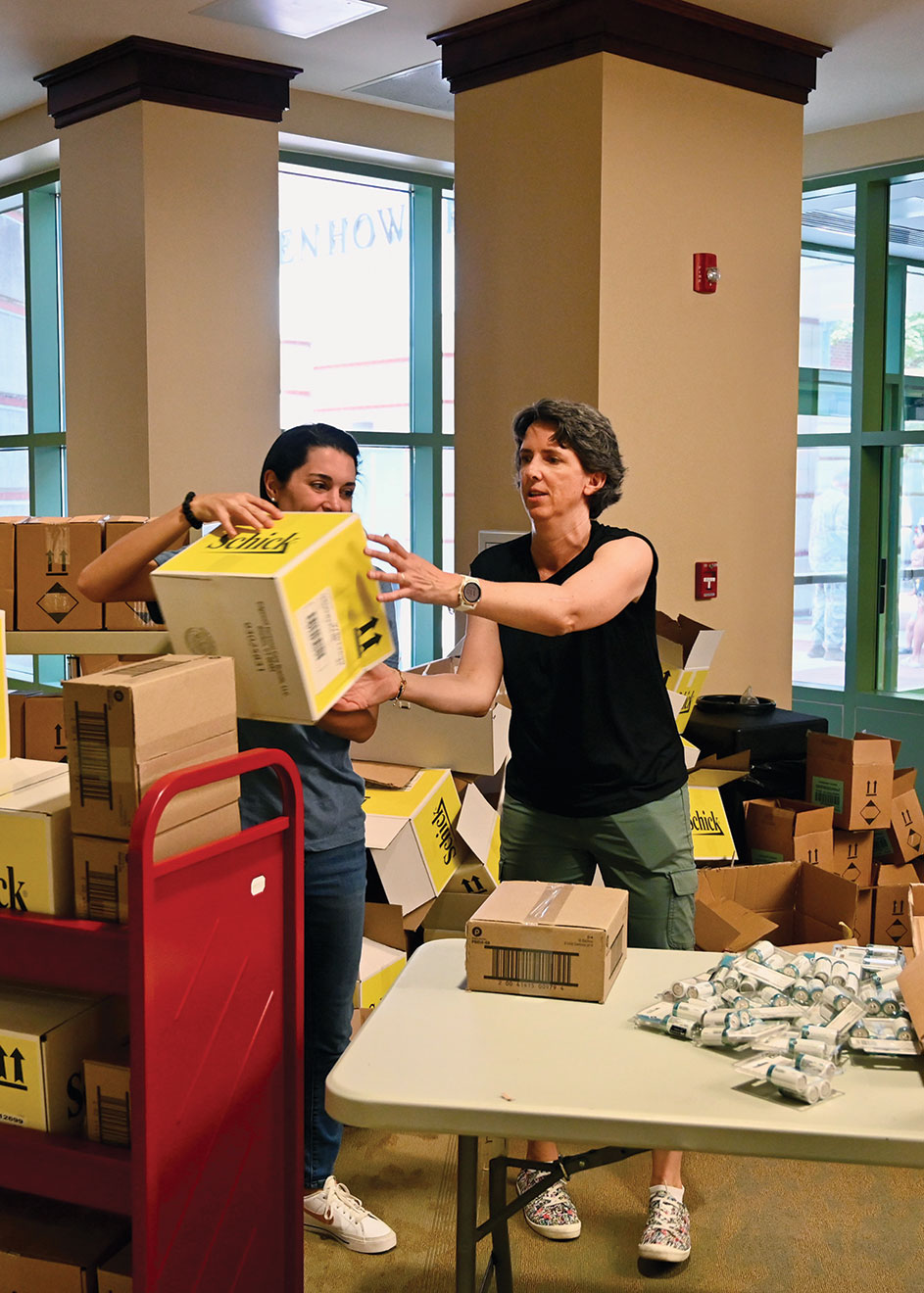 Library staff member Karen Wilson, left, and Foundation Assistant Director of Operations Laurie Morgado organize a station offering free personal hygiene products and other items provided by Foundation donors during the Ike Skelton Combined Arms Research Library open house on Aug. 11, 2023.