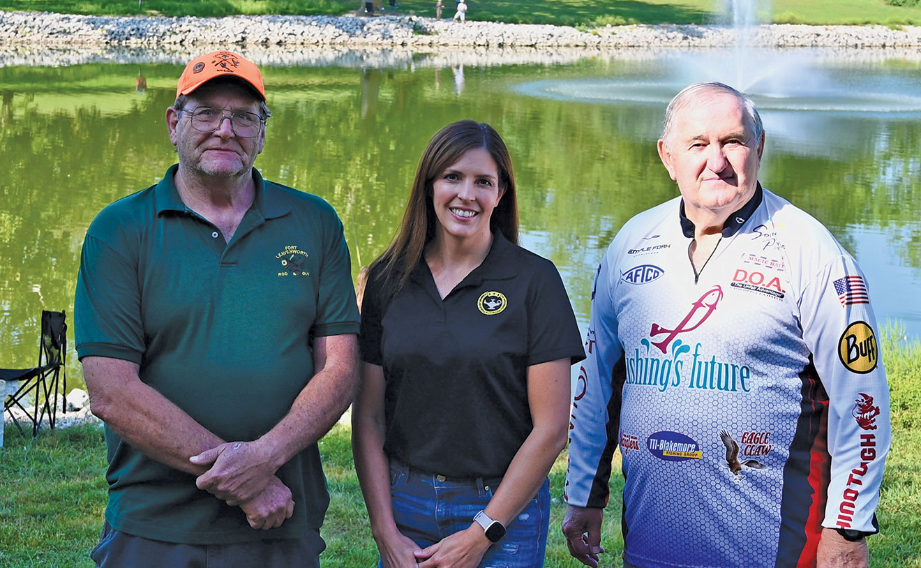 From left, Larry Noell, president of the Fort Leavenworth Rod & Gun Club, Lora Morgan, interim president/CEO of the CGSC Foundation, and Bill Horvath, an instructor with Fishing’s Future, gather for a photo opportunity as the third annual International Family Fishing Derby rages on in the background Sept. 9, 2023, at Merritt Lake on Fort Leavenworth. Noell and his club hosted the event and the CGSC Foundation and KAMO Adventures sponsored the fishing bait and concessions.