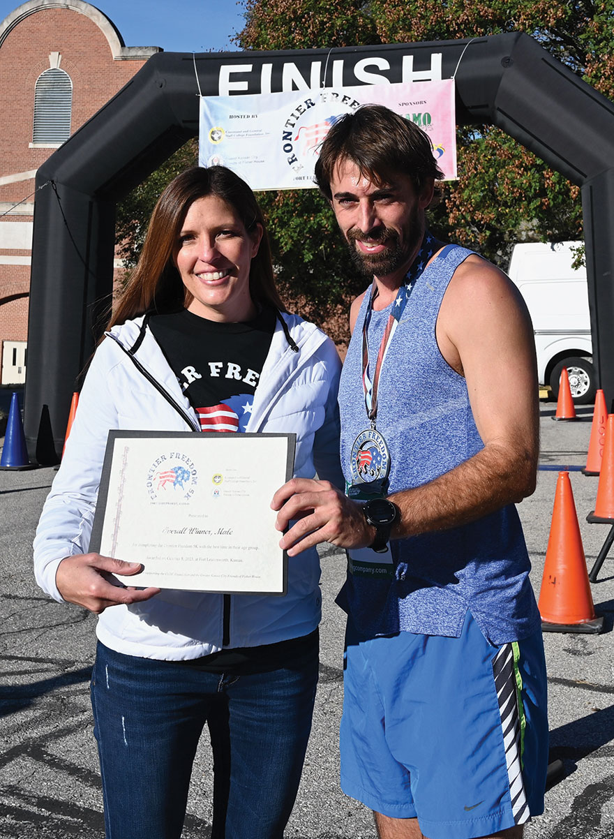 CGSC Foundation Interim President/CEO Lora Morgan, left, presents a certificate to Jacob Bull for his first place overall and top male division finish in the Frontier Freedom 5K Run/Walk on Fort Leavenworth on Oct. 8, 2023. The race was hosted by the CGSC Foundation and the Greater Kansas City Friends of the Fisher House.