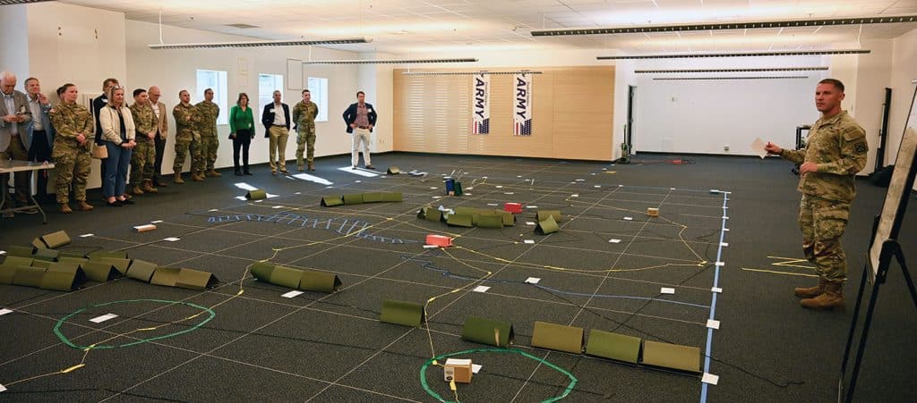 During a tour of the Lewis and Clark Center, guests of the National Security Roundtable conducted March 10-12, 2025, receive a briefing from Maj. Ben Keir, right, a student in the current Command and General Staff Officers Course. Keir provided the group with an orientation to a large “sand table” he and fellow students are using to rehearse and refine their plans in one of their class exercises.