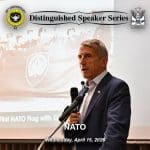 DSS-260415-article-600px Composite image with the Distinguished Speaker Series logo layered over an image of Major General William B. Hickman, U.S. Army, Retired, as he delivers his presentation on NATO, April 15, 2026, at the Riverfront Community Center, Leavenworth, Kansas.
