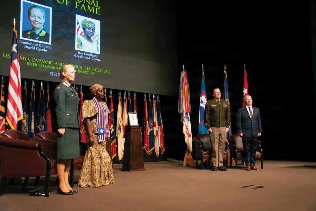 The U.S. Army Command and General Staff College International Hall of Fame inductees, left, Lieutenant General Ingrid Gjerde, Chief of Defence Staff, Vice Chief of Defence, Norwegian Armed Forces, and Minister Geraldine George, Minister of Defense of Liberia, and, right, Lt. Gen. Jim Isenhower, commanding general, U.S. Army Combined Arms Command and Fort Leavenworth, retired U.S. Army major general Christopher Hughes, chairman, Command and General Staff College Foundation, stand at attention during the induction ceremony April 9, 2026, on Fort Leavenworth. (U.S. Army photo by Jim Shea)
