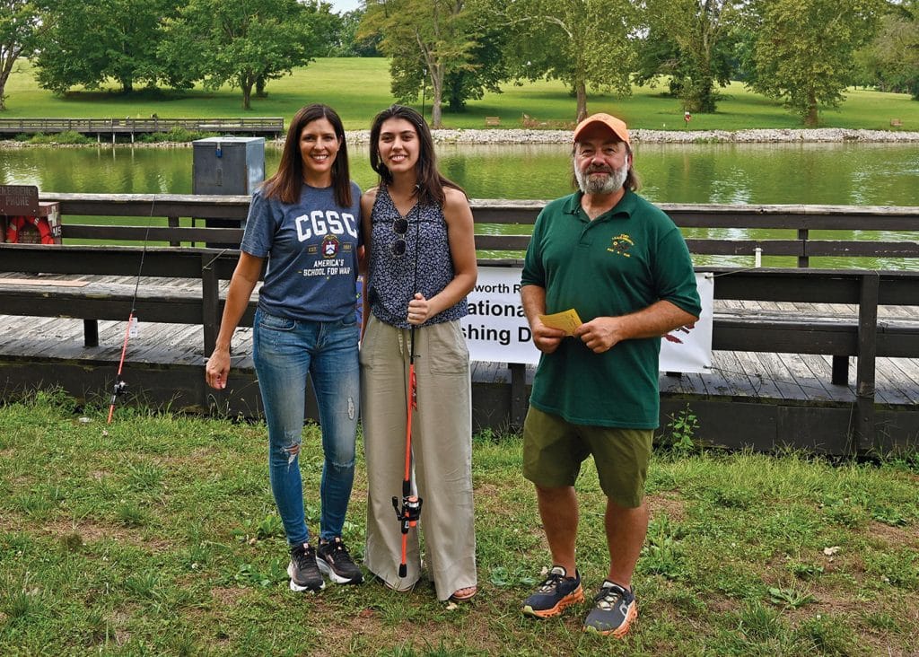 Lora Morgan, CGSC Foundation president/CEO, left, and Tad Slatter, Fort Leavenworth Rod & Gun Club, present Shafiga Kalbizada, wife of CGSOC international military student Capt. Eltaj Kalbizada from Azerbaijan, with a rod and reel combination for winning the Female Adult division at the International Family Fishing Derby Sept. 19, 2026, at Fort Leavenworth's Merritt Lake.